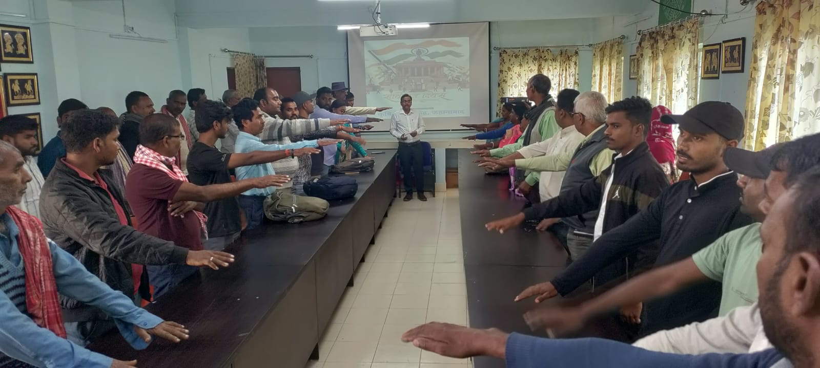 Community awareness session with participants taking a pledge indoors